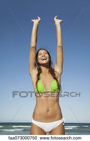 Stock Image - Woman in bikini stretching at the beach. Fotosearch
