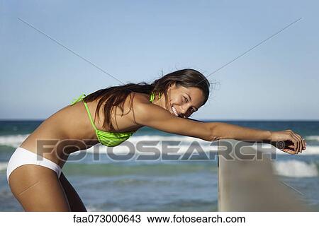 Stock Image - Woman in bikini stretching at the beach, portrait. Fotosearch