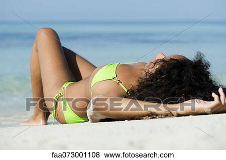 Woman in bikini sunbathing on beach View Large Photo Image Stock Photo - Woman in bikini sunbathing on beach. Fotosearch