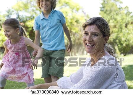 Woman laughing, children playing in background View Large Photo Image Stock Image - Woman laughing, children playing in background. Fotosearch