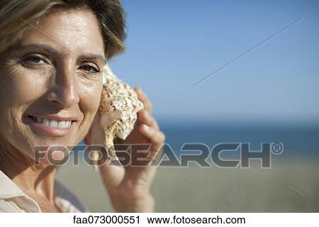 Woman listening to seashell, portrait View Large Photo Image Stock Image - Woman listening to seashell, portrait. Fotosearch
