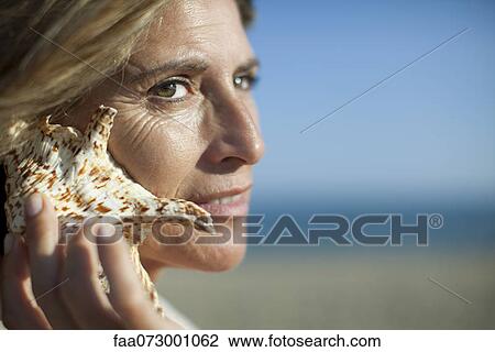Woman listening to seashell View Large Photo Image Stock Image - Woman listening to seashell. Fotosearch