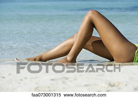 Stock Photography - Woman lying on beach, low section. Fotosearch
