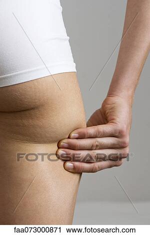 Stock Image - Woman pinching own buttock, cropped. Fotosearch