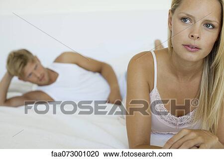 Woman relaxing on bed, man lying in background View Large Photo Image Stock Image - Woman relaxing on bed, man lying in background. Fotosearch