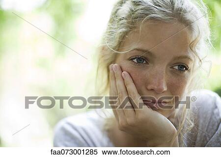 Stock Photography - Woman resting chin in hand, looking away in thought. Fotosearch