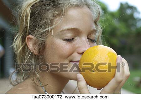 Stock Image - Woman smelling fresh orange. Fotosearch