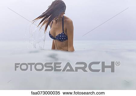 Stock Photography - Woman splashing in water, wet hair covering her face. Fotosearch