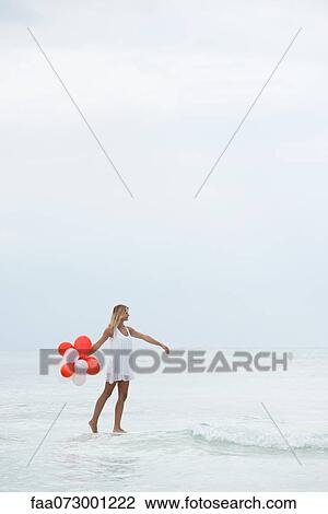 Woman walking on water, carrying bunch of balloons View Large Photo Image Stock Image - Woman walking on water, carrying bunch of balloons. Fotosearch