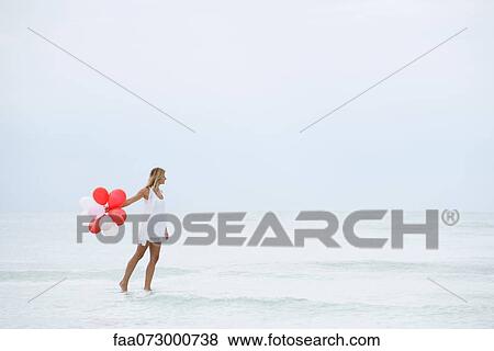 Woman walking on water, carrying bunch of balloons View Large Photo Image Stock Photo - Woman walking on water, carrying bunch of balloons. Fotosearch