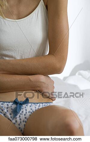 Stock Photo - Woman with arms across abdomen, mid section. Fotosearch