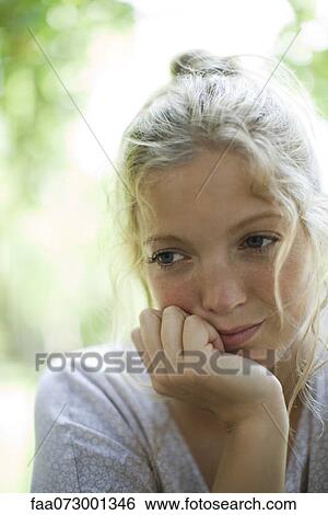Stock Photograph - Woman with chin resting on hand, looking away in thought. Fotosearch