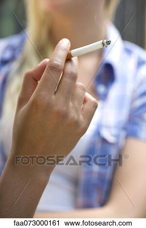 Stock Image - Woman's hand holding lit cigarette. Fotosearch