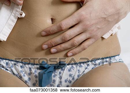 Stock Photo - Woman's hand on abdomen, close-up. Fotosearch