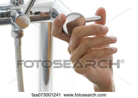 Stock Image - Woman's hand turning faucet. Fotosearch