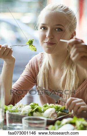 Stock Photograph - Young blond woman eating salad. Fotosearch