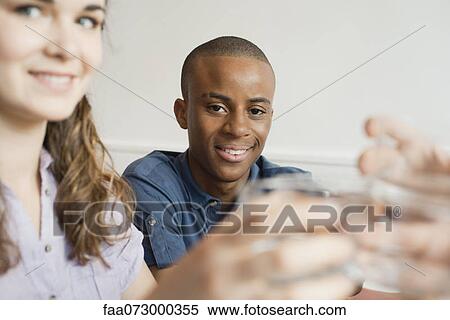 Stock Photography - Young man raising glass with friends. Fotosearch