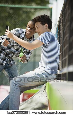 Stock Image - Young man showing cell phone to friend. Fotosearch