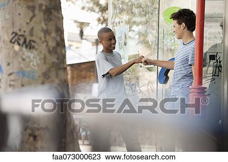 Stock Image - Young men greeting each other with fist bump. Fotosearch