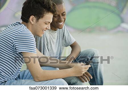 Young men looking at cell phone View Large Photo Image Stock Photo - Young men looking at cell phone. Fotosearch