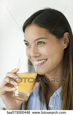 Stock Photo - Young woman drinking orange juice. Fotosearch