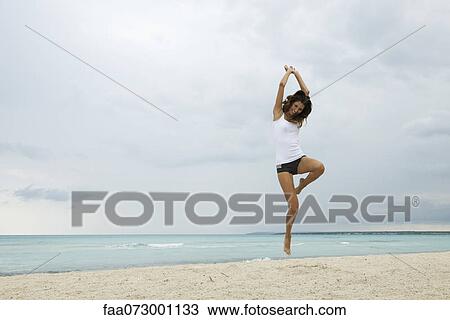 Young woman jumping in air on beach View Large Photo Image Stock Image - Young woman jumping in air on beach. Fotosearch