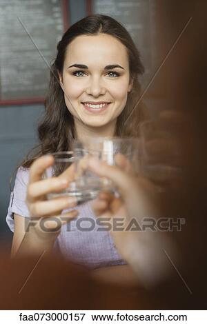 Stock Photo - Young woman raising glass with friend. Fotosearch