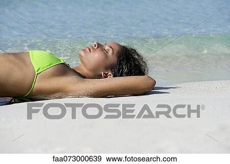 Stock Photo - Young woman sunbathing on beach. Fotosearch