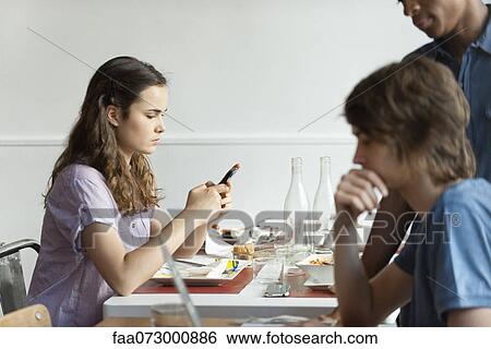 Young woman text messaging in restaurant View Large Photo Image Stock Photograph - Young woman text messaging in restaurant. Fotosearch