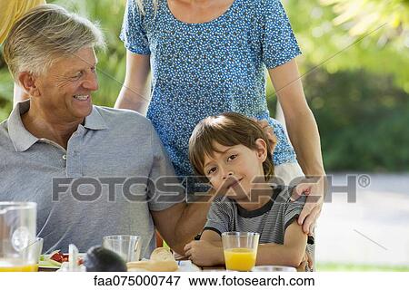 Boy and family having meal outdoors, cropped View Large Photo Image Stock Photo - Boy and family having meal outdoors, cropped. Fotosearch