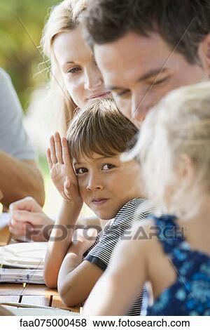 Stock Photo - Boy having meal with family outdoors. Fotosearch