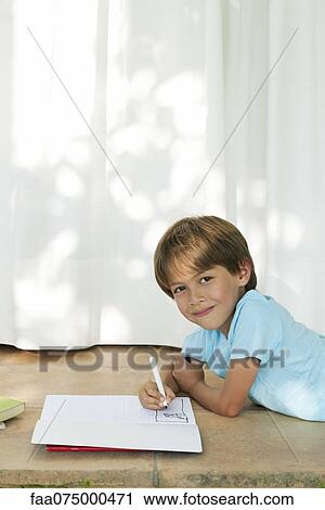 Boy lying on ground, drawing in notebook View Large Photo Image Stock Image - Boy lying on ground, drawing in notebook. Fotosearch