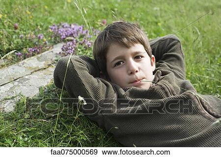 Stock Photo - Boy relaxing on grass, portrait. Fotosearch