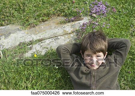 Boy relaxing on grass, portrait, directly above View Large Photo Image Stock Photograph - Boy relaxing on grass, portrait, directly above. Fotosearch