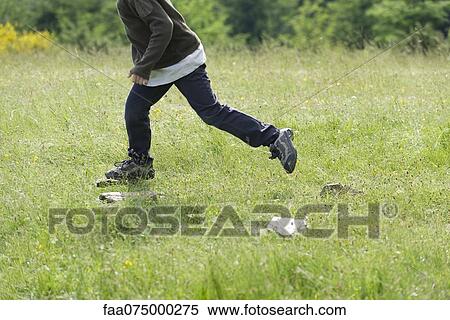Stock Photography - Boy running in meadow, low section. Fotosearch