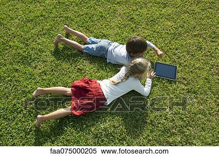 Children lying on grass, using digital tablet together View Large Photo Image Stock Photography - Children lying on grass, using digital tablet together. Fotosearch