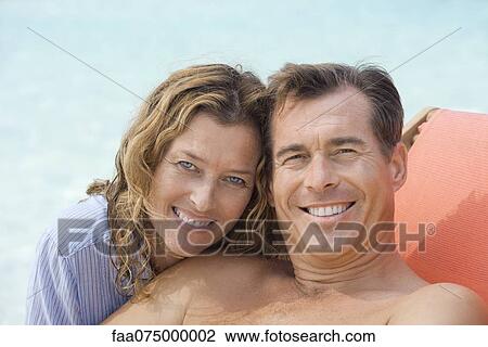 Stock Image - Couple relaxing at beach, portrait. Fotosearch