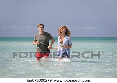 Couple standing knee deep in water, holding hands View Large Photo Image Stock Photo - Couple standing knee deep in water, holding hands. Fotosearch