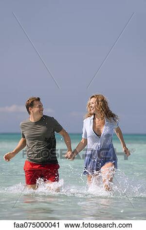 Couple walking in water, holding hands View Large Photo Image Stock Image - Couple walking in water, holding hands. Fotosearch