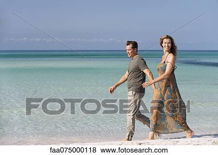 Stock Photo - Couple walking leisurely on beach. Fotosearch
