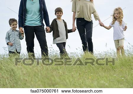 Stock Image - Family holding hands together outdoors, cropped. Fotosearch