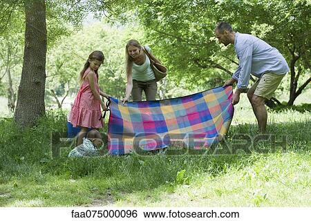 Stock Photograph - Family preparing for picnic in meadow. Fotosearch