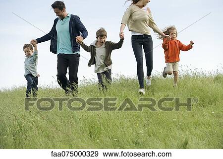 Family running hand in hand in field View Large Photo Image Stock Photo - Family running hand in hand in field. Fotosearch