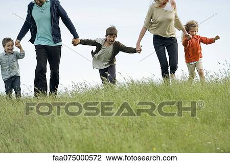 Family running together hand in hand in field View Large Photo Image Stock Image - Family running together hand in hand in field. Fotosearch