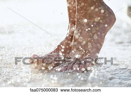 Stock Image - Feet under shower outdoors. Fotosearch