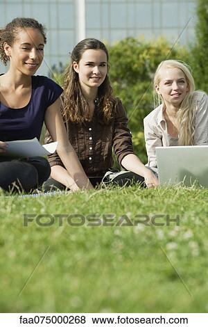 Female university students studying together on grass, low angle view View Large Photo Image Stock Photo - Female university students studying together on grass, low angle view. Fotosearch