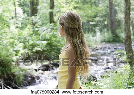 Girl by stream in woods, looking away View Large Photo Image Picture - Girl by stream in woods, looking away. Fotosearch