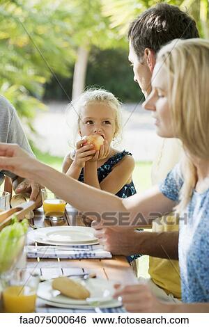 Girl having meal with family outdoors View Large Photo Image Stock Photograph - Girl having meal with family outdoors. Fotosearch