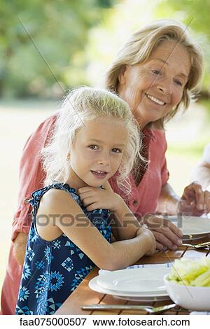 Stock Photo - Girl having meal with grandmother outdoors. Fotosearch