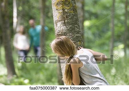 Stock Photo - Girl hiking behind tree in woods. Fotosearch